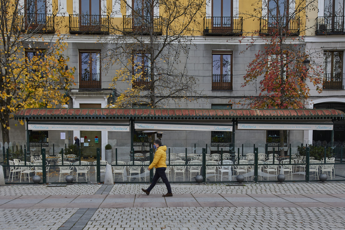 Unha persoa pasea á beira dun biombo instalado nun restaurante da Praza de Oriente, en Madrid (España), ao 12 de novembro de 2020. A Comisión de Terrazas da capital acordou onte unha resolución pola que se permite, de forma temporal, ínstaa