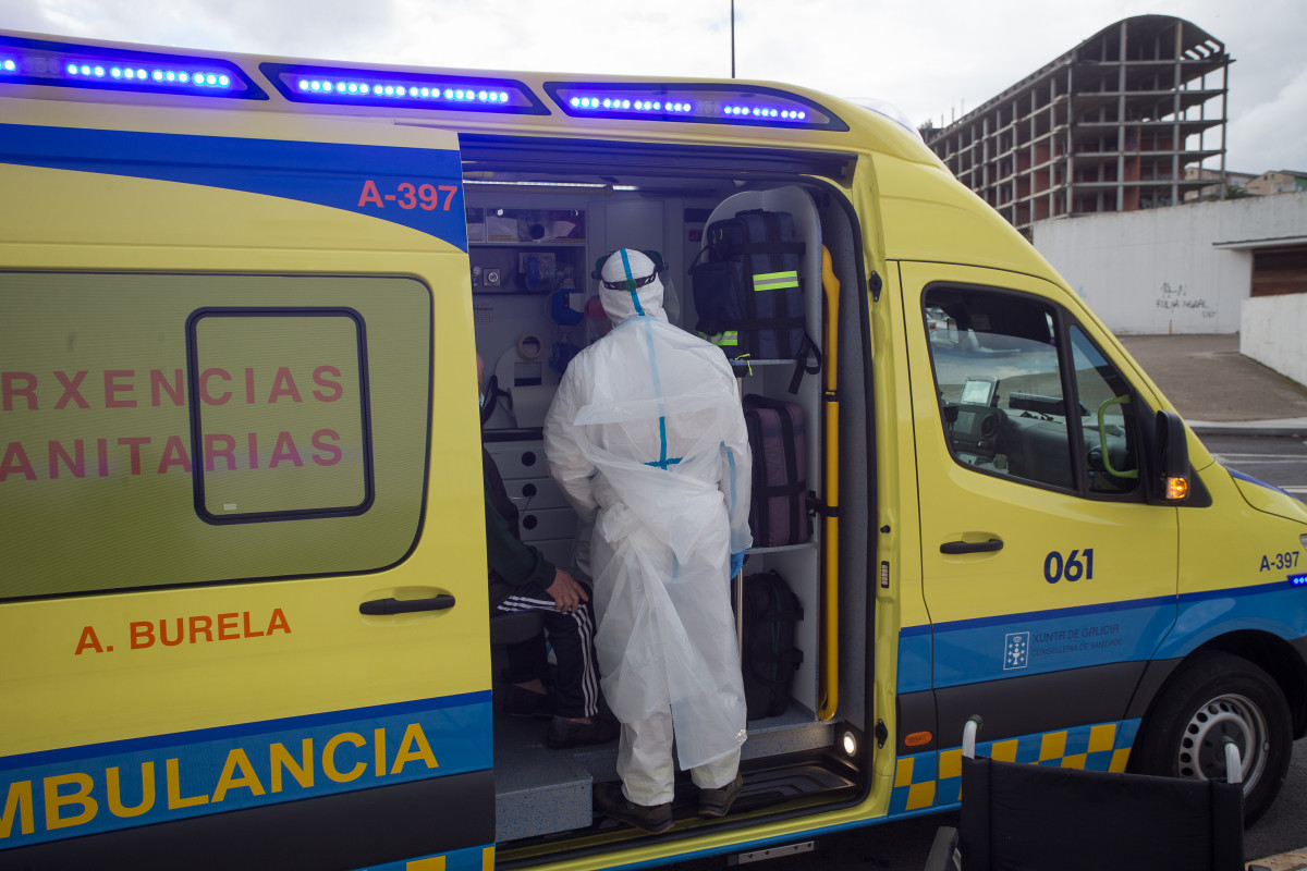 Un traballador sanitario totalmente protexido axuda a subir á ambulancia a un ancián da residencia de anciáns de San Cibrao onde se orixinou un brote de Covid-19, en San Cibrao, Lugo, Gali