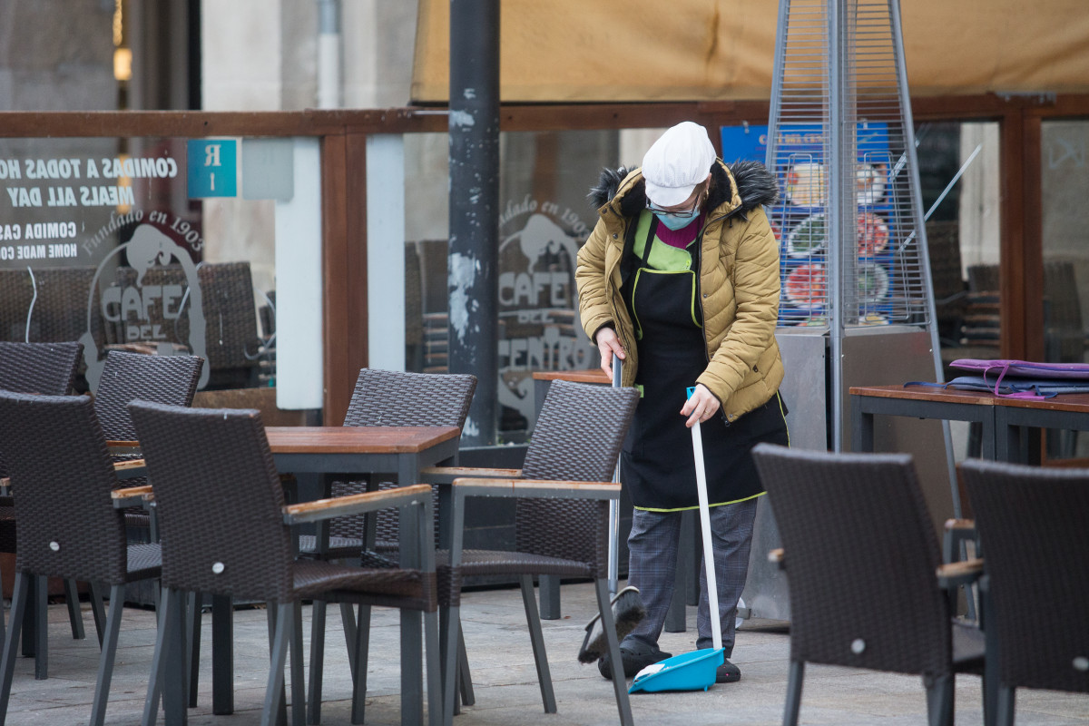 Unha muller varre a terraza dun restaurante o primeiro día do peche perimetral decretado en Lugo, Galicia (España), ao 15 de xaneiro de 2021.
