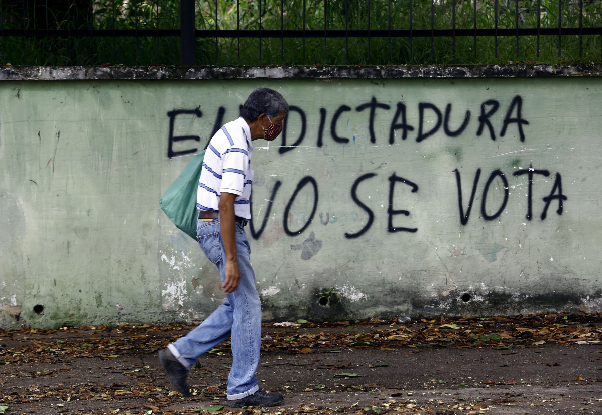 Un home pasea xunto a un mural contra as eleccións parlamentarias de Venezuela