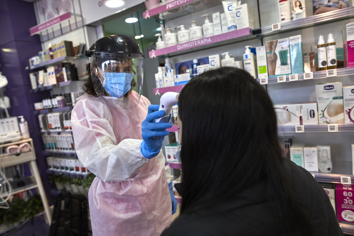 Unha farmacéutica toma a temperatura a unha muller antes de realizarlle un test de antígenos na Farmacia As Xemelgas en Madrid (España), ao 11 de febreiro de 2021. O pasado mércores 3 de febreiro, 