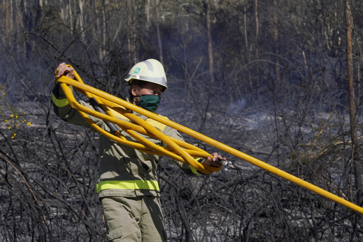 Un bombeiro apaga o incendio forestal na parroquia de Figueriras en Santiago de Compostela, A Coruña, Galicia (España), ao 20 de marzo de 2021. O incendio, xa estabilizado, orixinouse ao redor de