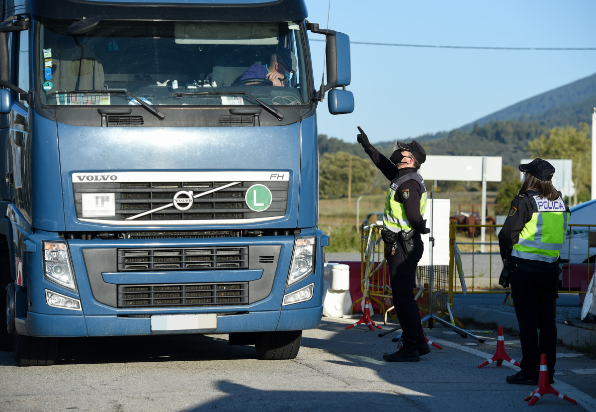 Un axente dá o alto a un camión nun punto fronteirizo entre Portugal e España onde están a realizar controis de mobilidade, ao 5 de abril de abril de 2021, en Zarza la Mayor, Cáceres, (España).