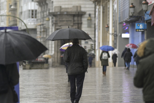 Arquivo - Transeúntes camiñan protexidos por unha vía da Coruña, Galicia (España), ao 20 de xaneiro de 2021. O temporal de neve e posterior frío provocado pola borrasca 'Filomena' terminará este martes cando esta pase a testemuña a unha nova fronte, baut