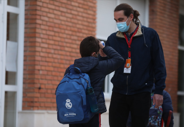 Un traballador toma a temperatura a un neno á súa chegada ao primeiro día de clase presencial tras o Nadal