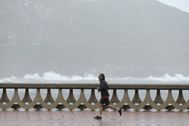 Un home, con chubasquero, corre polo Paseo Marítimo da Coruña, ao 19 de xuño de 2022, na Coruña