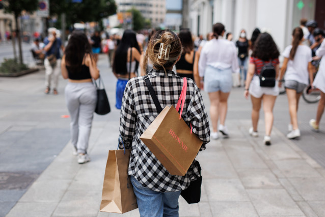 Unha muller pasea con bolsas de firmas de moda pola Gran Vía, ao 21 de xuño de 2022, en Madrid (España).