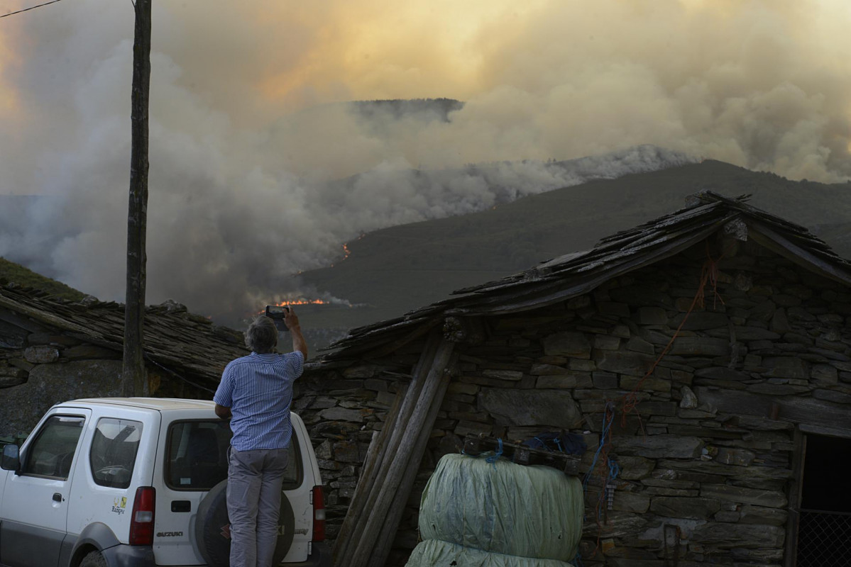 Un home fotografa as chamas do incendio, ao 10 de agosto de 2022, en Laza, Ourense, Galicia (España). Segundo a última actualización provisional da Consellería do Medio Rural, no munici