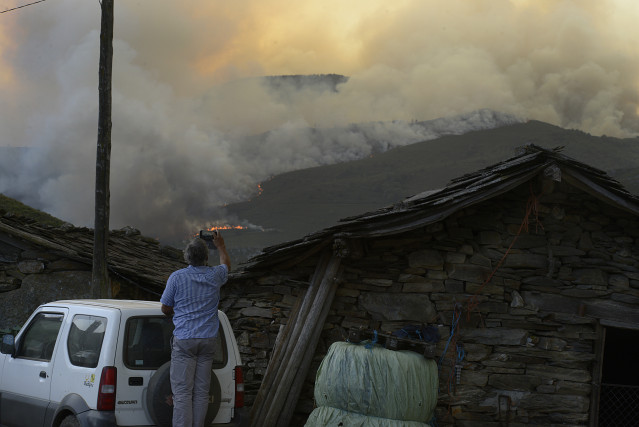 Un home fotografa as chamas do incendio, ao 10 de agosto de 2022, en Laza, Ourense, Galicia (España).