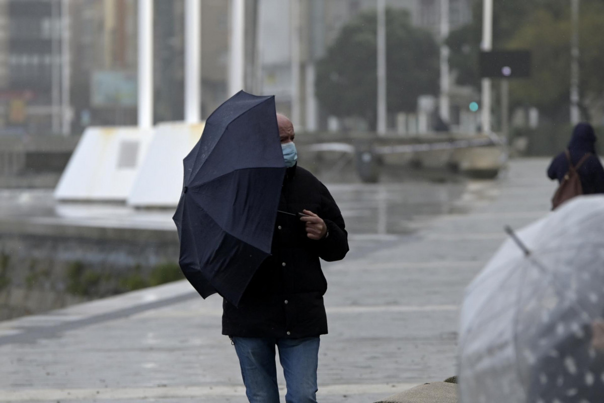 Archivo - Un hombre con un paraguas camina por el paseo marítimo mientras llueve, a 8 de diciembre de 2021, en A Coruña, Galicia, (España). La borrasca Barra ha hecho que la Xunta haya activado par