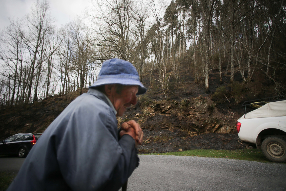 Un hombre camina junto al monte quemado por un incendio forestal, a 30 de marzo de 2023, en Baleira, Lugo