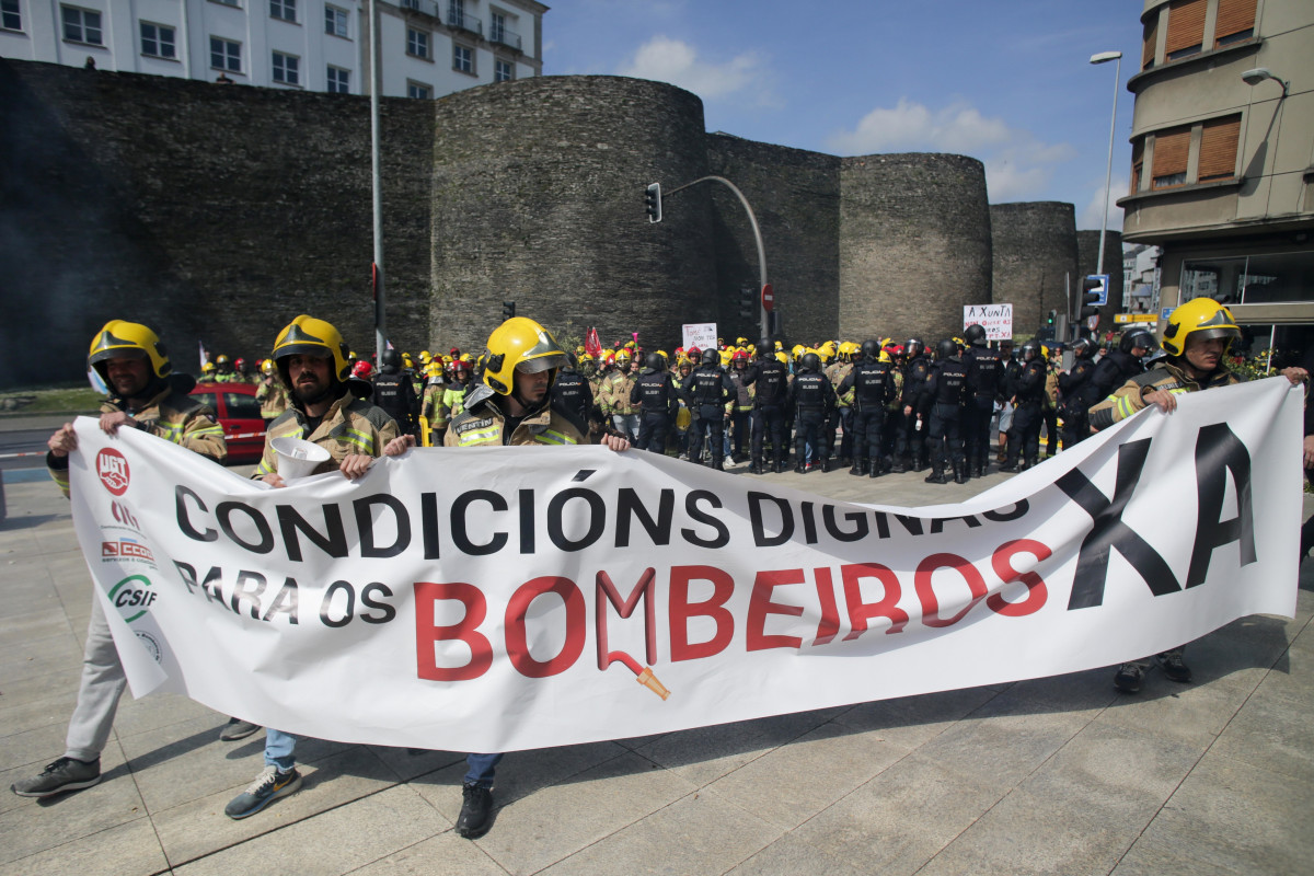 Un grupo de bomberos de consorcios provinciales sujetan pancartas durante una protesta ante la sede de la Xunta, a 23 de mayo de 2023, en Lugo, Galicia (España). Los bomberos de consorcios provincial