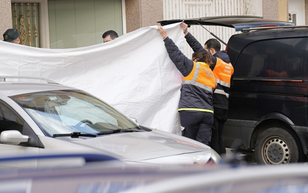 Dos agentes de Protección Civil tapan con una lona la zona donde se han encontrado los cuerpos de dos octogenarios en Sigüeiro.