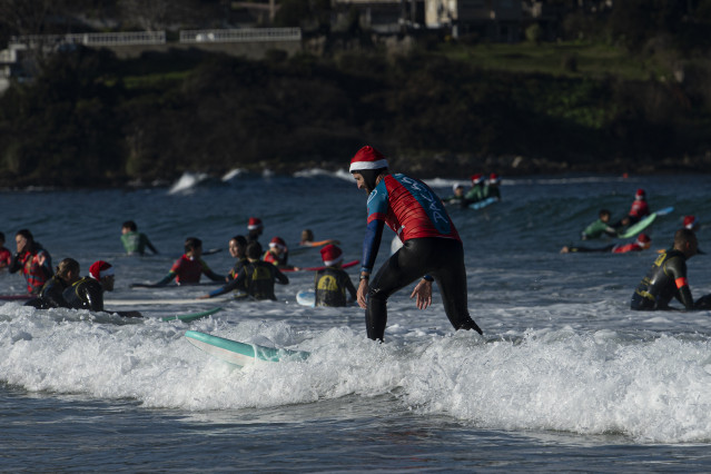 Un hombre disfrazado de Papá Noel surfea durante la Papanoelada Surfera, en la playa de Patos, a 23 de diciembre de 2023, en Nigrán, Pontevedra, Galicia (España).