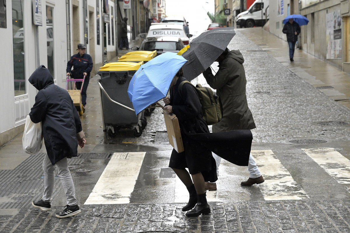 Varias personas se refugian del viento con paraguas, a 8 de febrero de 2024, en A Coruña, Galicia (España). El paso de la borrasca Karlotta por Galicia está provocando a lo largo del día de hoy in