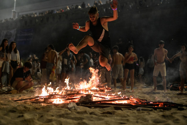 Archivo - Una persona salta una hoguera durante la Noche de San Juan, en la playa de Riazor, a 23 de junio de 2023, en A Coruña, Galicia.