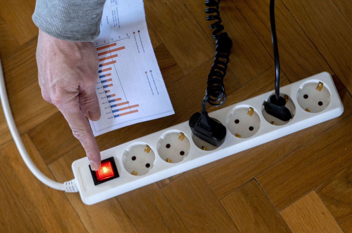 Archivo - Un hombre enciende una largadera con varios enchufes con una factura de luz en la mano, a 3 de enero de 2022, en Madrid, (España). El precio medio de la electricidad en el mercado mayorista