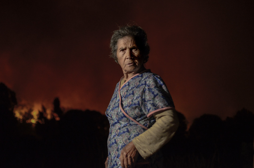 Una mujer ante un incendio en una imagen de la expo de Brais Lourenzo